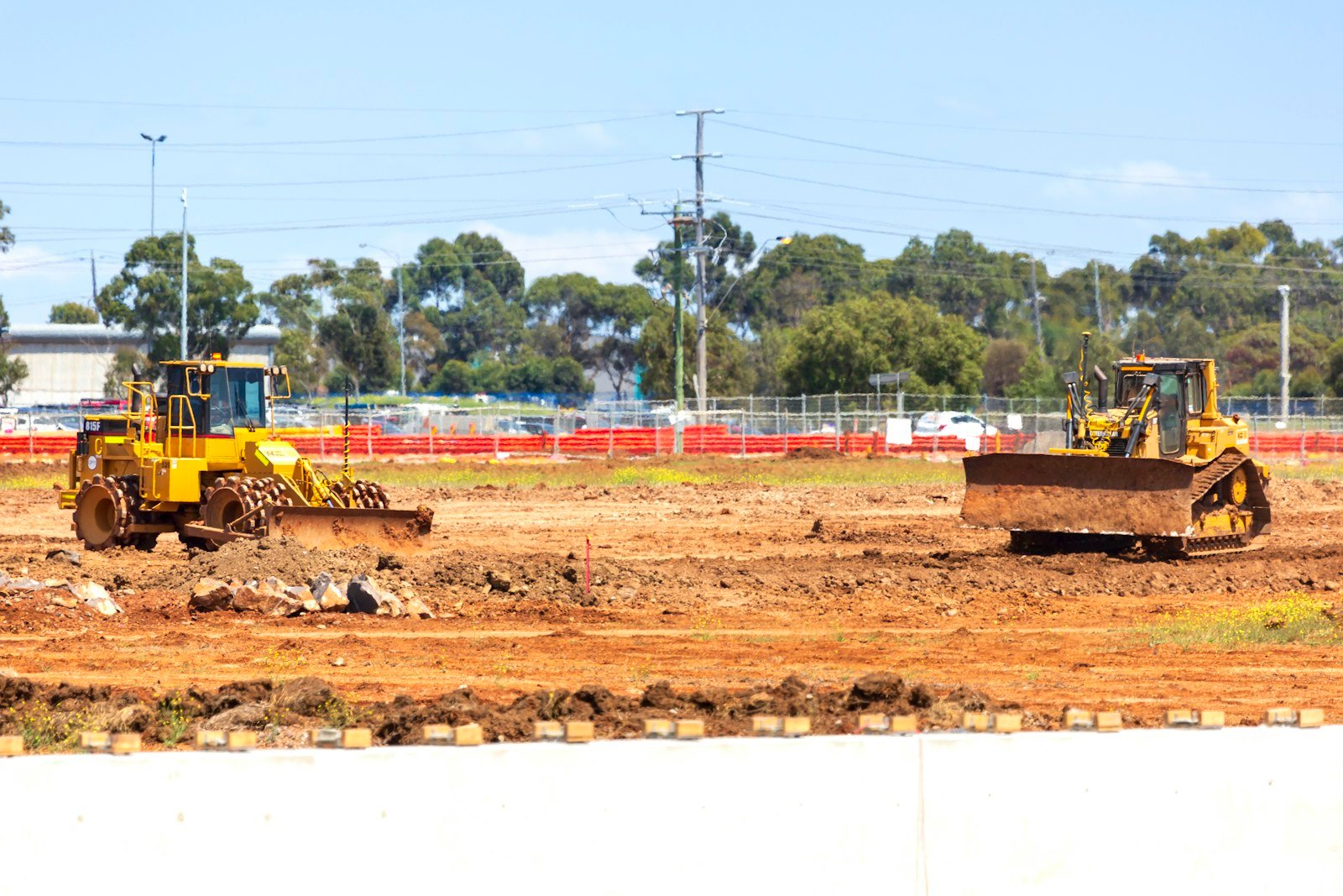 A loader and a bulldozer working a graded construction site, representative of heavy equipment consignments