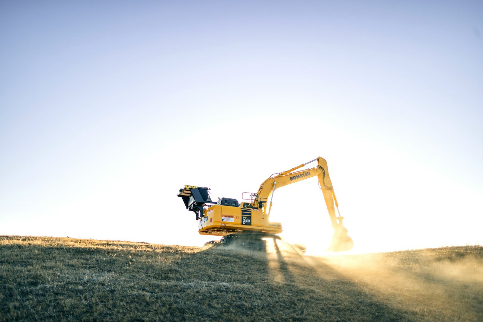 Excavator on a dirt hillside against a clear sky, representative of the kind of commercial equipment consigned at auction