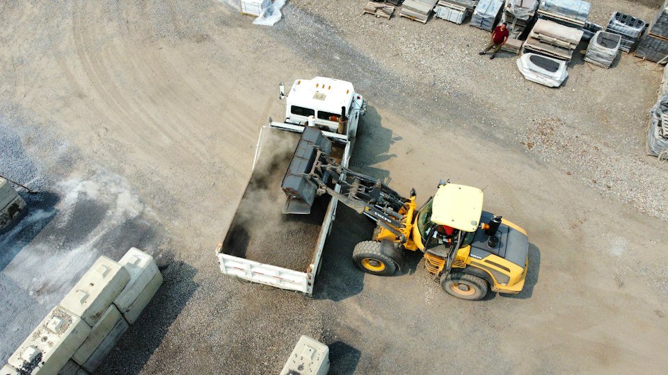 Front loader moving material into a truck, representative of yard and site equipment consignments