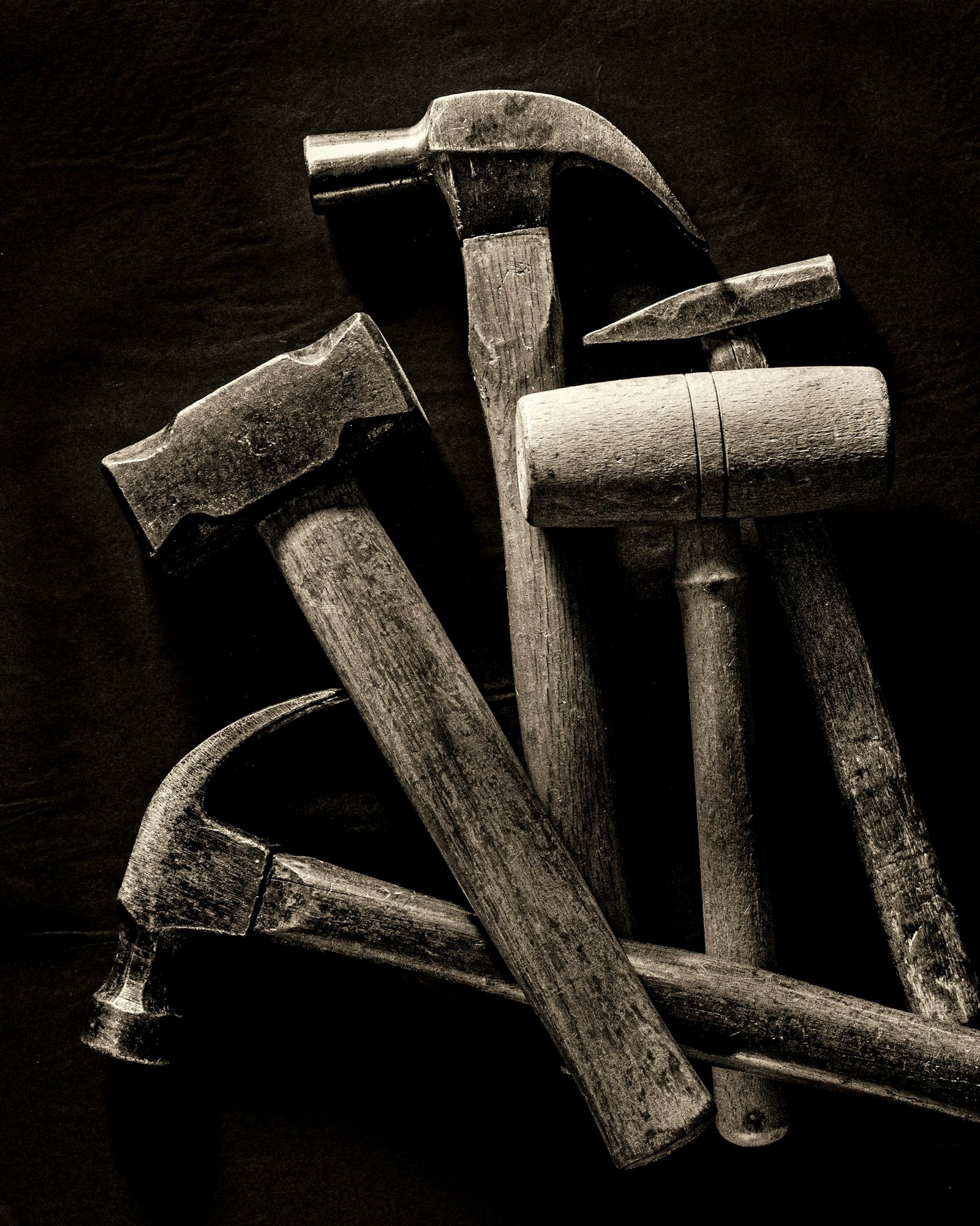 A small set of hammers arranged on a dark surface, representative of an estate tool lot