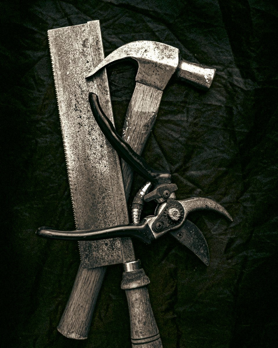 A small set of hand tools arranged on a dark surface, representative of an estate tool lot