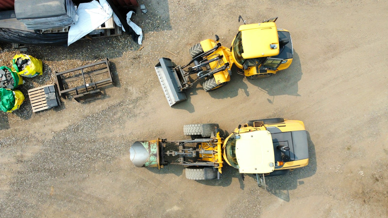 Aerial view of construction equipment staged in a dirt storage yard, representative of equipment staged for auction